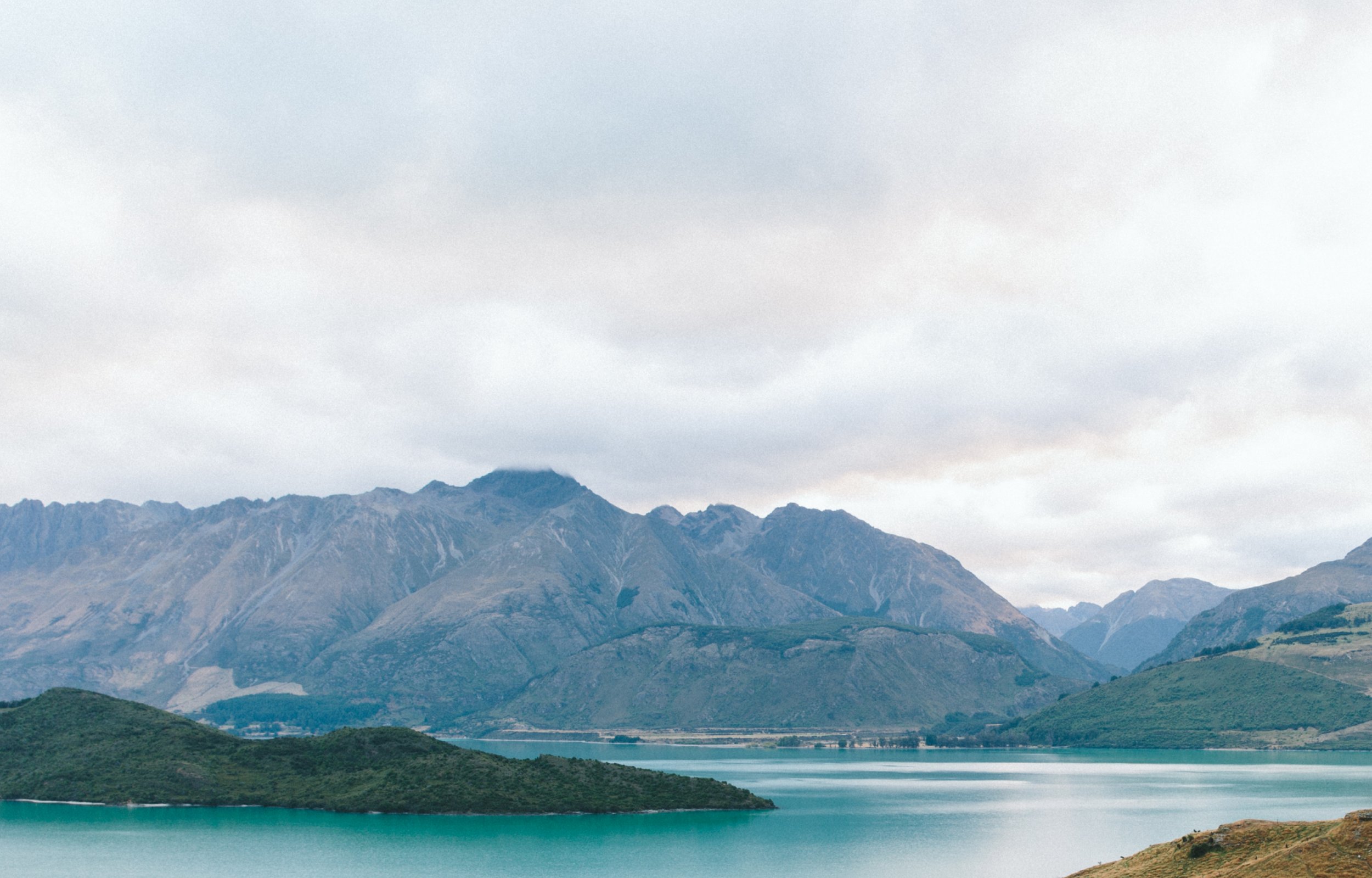 A landscape of mountains, a lake, and cloudy sky.
